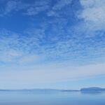Small icebergs float near the coastline under a cloudy sky in the eastern Arctic, Canada.
