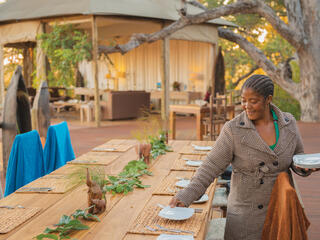 Catherine Mafumelo sets plates on an outdoor table
