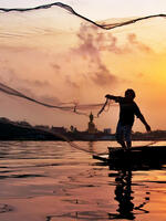 Fisher casts a line at sunset on Chaophaya River