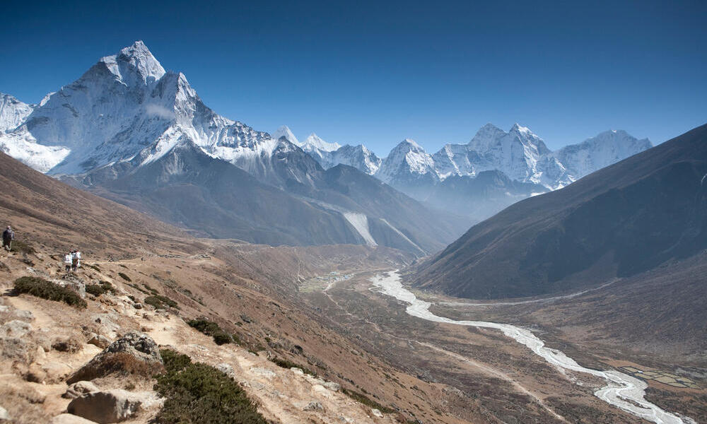 Landscape view of a river in a deep valley with snowcapped mountains in the background