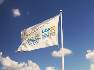 A white flag against a blue sky displays the logo for COP27