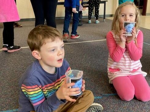 Children sit on the floor listening to instructions