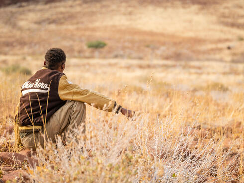 Man crouching in tall grass looking at landscape