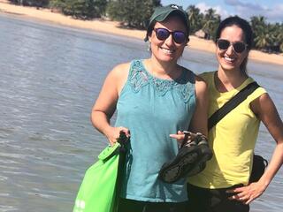 Shauna and Gabby smile at the camera with their arms around one another in front of the ocean in Madagascar