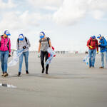 people picking up trash on a beach