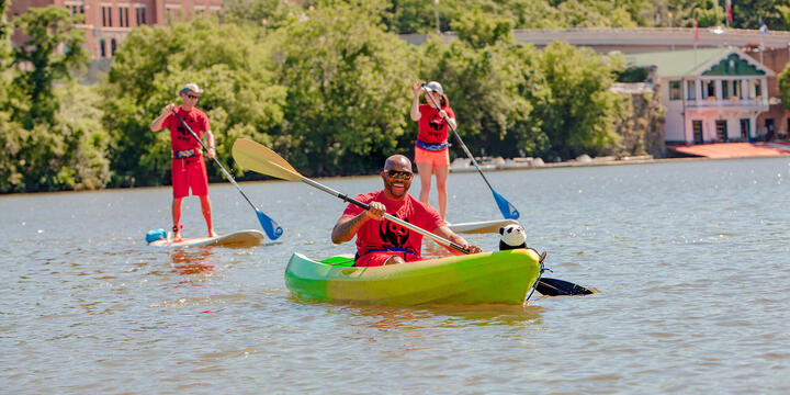 River with a kayaker in the foreground and two stand up paddle boarders in the background