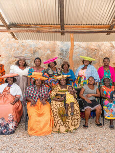 A group of women in colorful traditional dress, seated for portrait