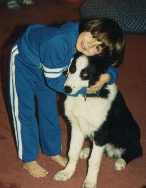 Alexis Will as a kindergarten student hugging her black and white dog