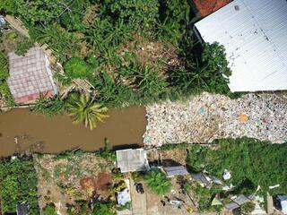 Aerial view of plastics clogging a river between homes in Indonesia