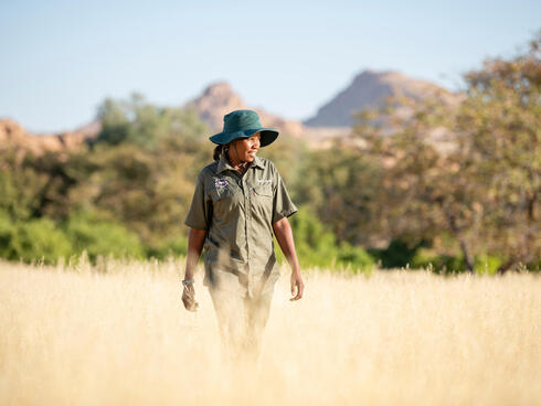 Female ranger walking in tall grass