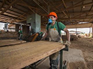 Man with mask sawing timber