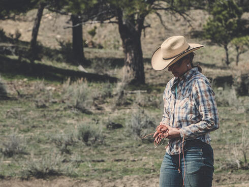 Heather Bilden looks down at her hands in a grassy area with trees.