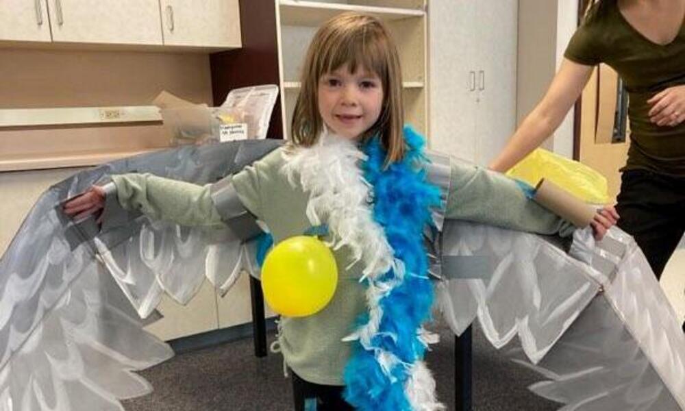 A child dresses up as a seabird wearing a bunch of feathers