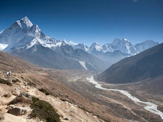 Landscape view of a river in a deep valley with snowcapped mountains in the background