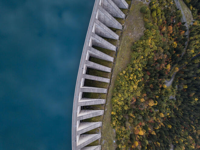 Aerial view of a hydropower dam with water on one side and forest on the other