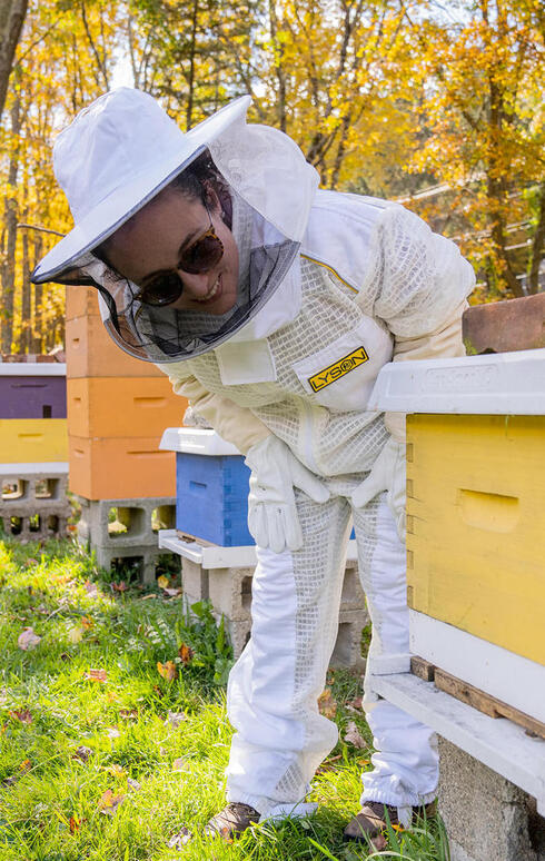 Julia Kurnik dressed as beekeeper, inspecting hive