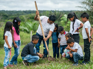 School teacher during a practical lesson outside of the classroom, planting trees in the school grounds