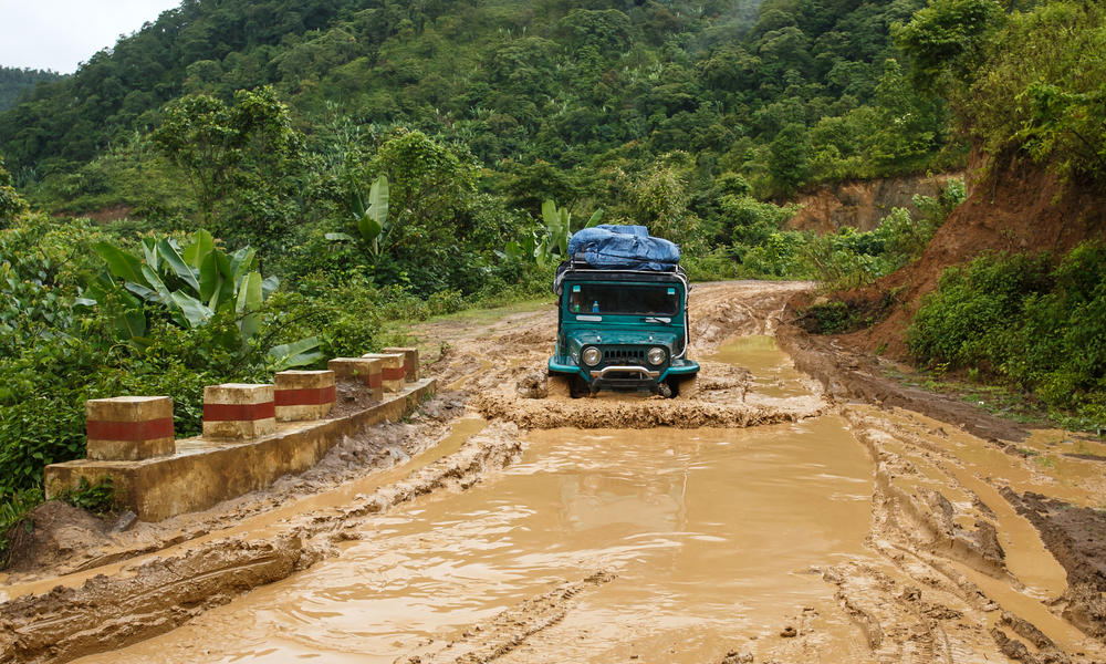 Car driving through a flooded and muddy road