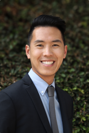 Alex Yee smiles, wearing a suit and tie.