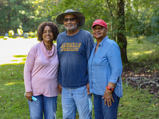 A family of three stands together facing the camera