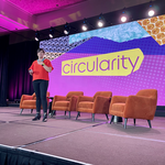 Erin Simon stands on a stage in front of a screen reading "circularity" 